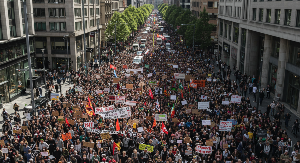 Large crowd of protesters holding placards and chanting slogans in a busy city street, captured in daylight #2