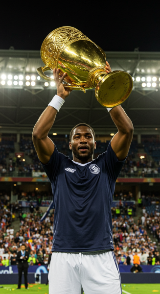 A champion lifting a golden trophy under stadium lights