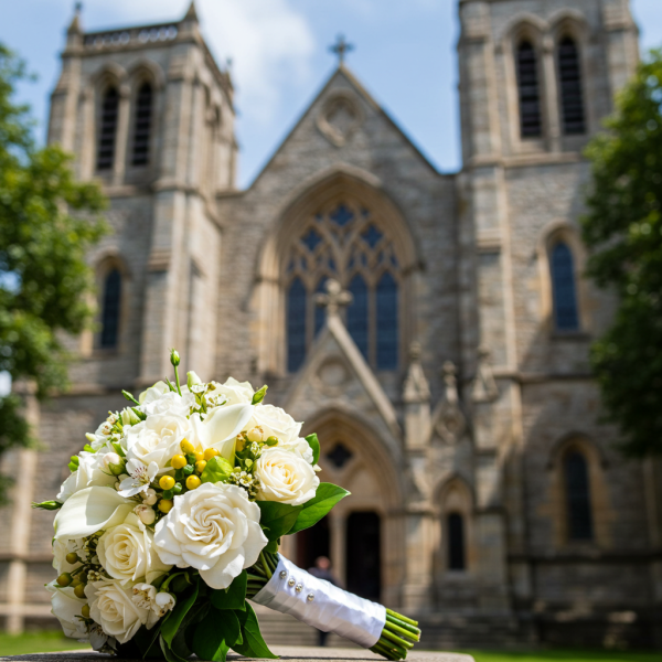 A white wedding bouquet in front of a church #2