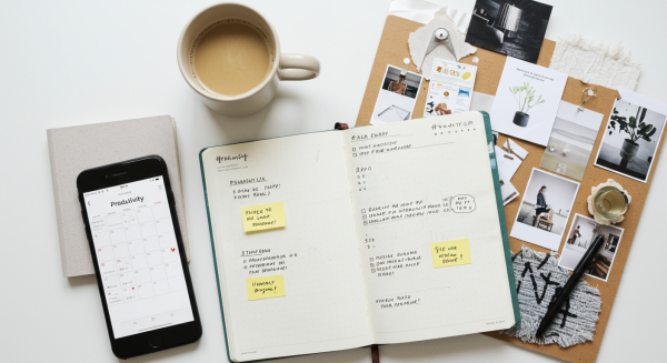 Flat lay of phone, planner, coffee, and mood board on white workspace #1