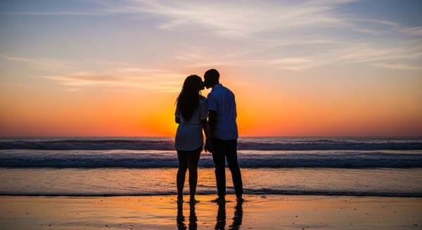 A shot of a young black man and woman kissing at the beach at dusk #1