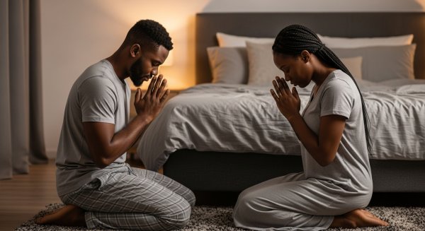 A black man and a black woman on their knees, praying by their bed #1