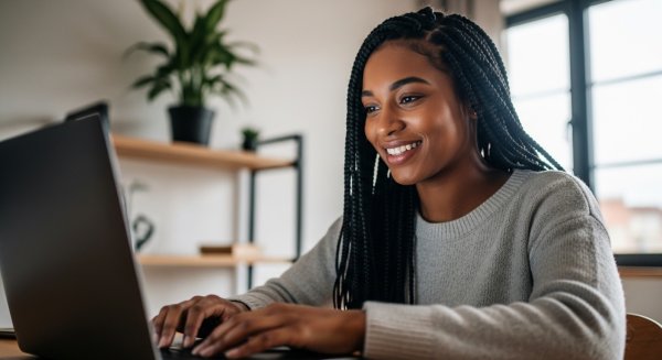 A young, pretty black lady sitting behind her laptop and smiling #3
